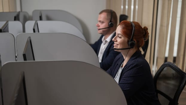 Two friendly call center employees answer customers by phone. Man and woman woman talking on a headset in the office