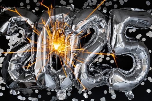 Happy new year 2025 metallic balloons with confetti and sparkler firework Bengal lights on dark black background. Greeting card silver foil balloons numbers Christmas holiday concept. Celebration party congratulation decoration