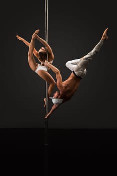 Studio photo of sporty people dancing on pole in pair