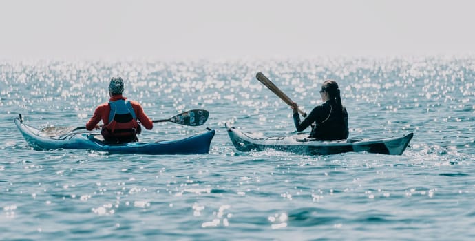 Happy smiling woman in kayak on ocean, paddling with wooden oar. Calm sea water and horizon in background