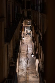 Atmospheric narrow alleyway at night, illuminated by dim streetlights and cobblestone path, creating a vintage city vibe.