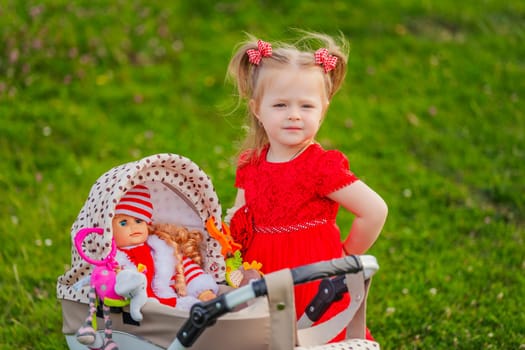 a child with a toy stroller and a doll is playing in nature