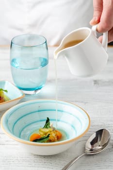 Fish soup with vegetables on white wooden table