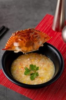 Crab soup in black porcelain plate on gray stone table