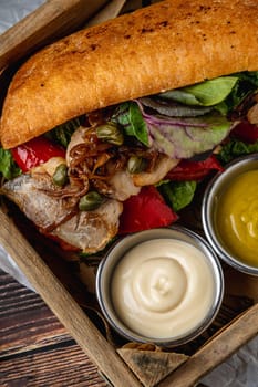 Steak sandwich with sauces and french fries on wooden table