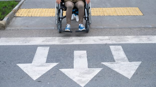 An elderly woman in a wheelchair is about to cross the road at a pedestrian crossing