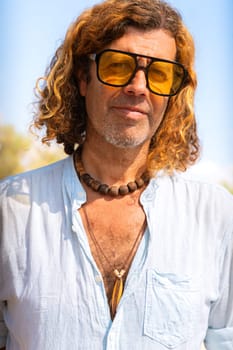 Caucasian adult man wearing smiling sunglasses looking at camera. Man on vacation on the coast.