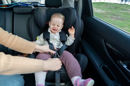 Crying toddler girl sitting in safety car seat