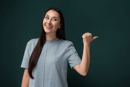 A woman is pointing with her finger, indicating something off-camera. She appears to be directing attention towards a certain object or area, her body language showing a clear focus on whatever she is pointing at.