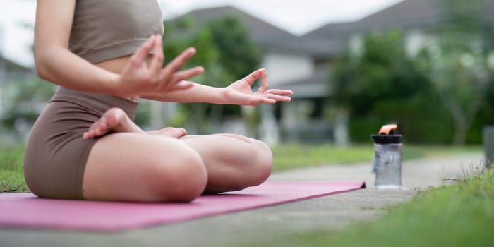 A young woman practice yoga in a park, focusing on stretching and meditation for a healthy lifestyle and fitness.