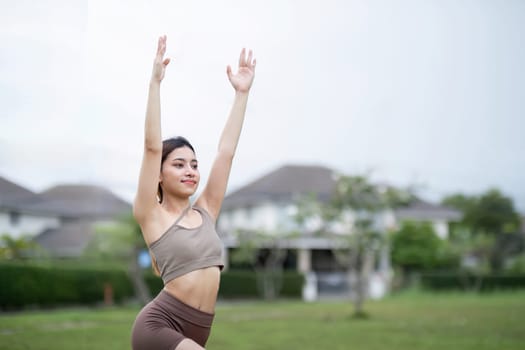 A young woman performing yoga stretches in a park, showcasing a healthy and active lifestyle. Ideal for promoting fitness, wellness, and outdoor activities.