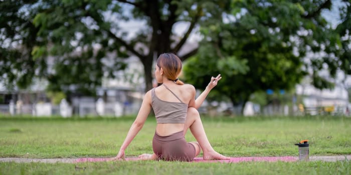 Woman practice yoga in a park, focusing on stretching and relaxation. Embracing a healthy lifestyle through outdoor exercise.