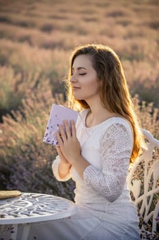 A woman in a white dress is sitting at a table with a book in her lap. She is in a peaceful and relaxed state, possibly reading the book or meditating. The scene is set in a field of lavender