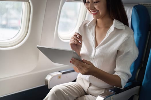 Business professional using a tablet on an airplane, showcasing in-flight productivity and modern business travel.