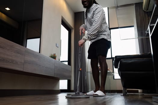 A man mopping the floor in a modern home, showcasing daily cleaning routines and home maintenance in a contemporary living space.