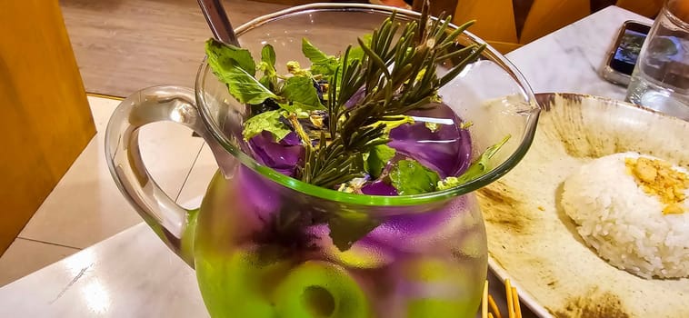 Two colored cocktail drink with blueberry and melon syrup taste in a pitcher served with herbs and mint leaves and ice cubes, good cocktail recipes good for drink content creation