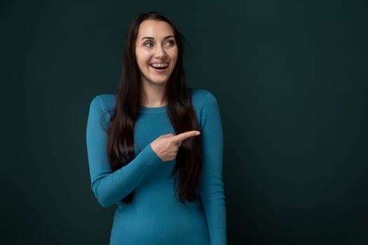 A woman wearing a blue dress is pointing at an unseen object in the distance. Her action suggests she is directing attention towards a specific point or item.