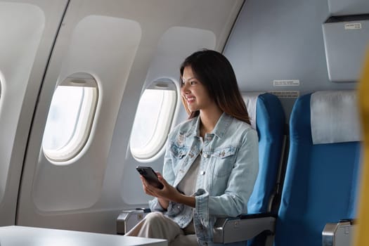 Professional woman using smartphone on business airplane, showcasing modern air travel and in-flight connectivity for corporate travelers.