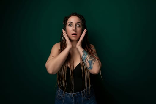 A woman with dreadlocks covering her face, partially obscuring her features. The dreadlocks cascade down in a tangled mass, creating a veil over her eyes and nose. Her hands are visible, attempting to push back the hair from her face.