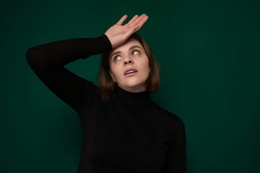 A woman wearing a black turtle neck top is shown in the image, with her hands raised up to her head in an evident expression of distress or confusion. The womans body language suggests a sense of overwhelm or frustration.