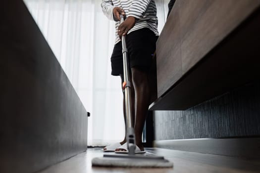 Close-up of a person mopping the floor in a modern home, showcasing cleaning tools and a tidy living environment.