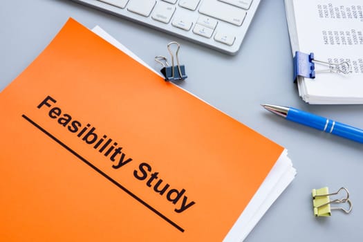 Stack of papers with feasibility study and a keyboard.