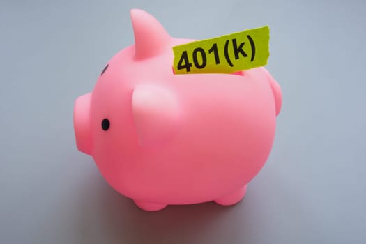 Pink piggy bank with inserted word 401k about pension plan.