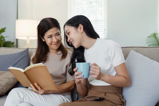 A touching scene of a mother and daughter sharing a special moment on Mother's Day, enjoying a book and coffee together on a comfortable sofa.
