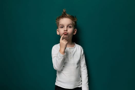 A young female child is standing in front of a vibrant green wall, looking directly at the camera. She appears curious and engaged, with a slight smile on her face.