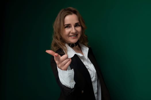 A woman wearing a black jacket is pointing directly at the camera. She appears to be making a gesture, possibly to emphasize a point or draw attention. Her body language is assertive and confident.