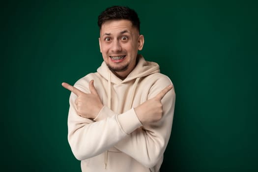 A man wearing a hoodie is seen making a gesture with his hands. His facial expression is focused as he communicates non-verbally through his hand movements.