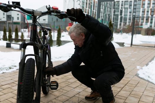 Senior man checking the operation of a bicycle on the street.