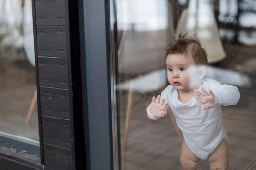 Baby boy standing by the patio window