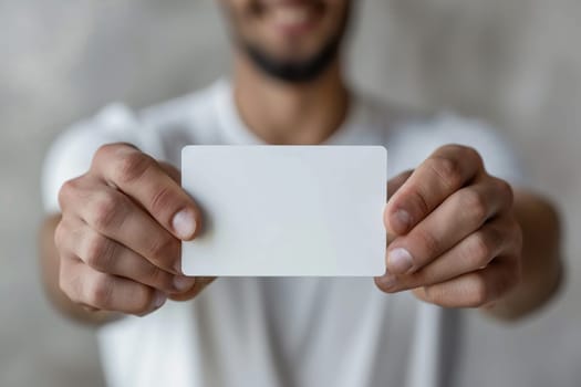 A blank white bank card or business card in the hands of a man close-up.