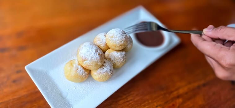 Homemade delicious sweet Dutch poffertjes mini pancakes with icing powdered sugar and chocolate fillings with additional chocolate sauce for cooking multimedia content creation