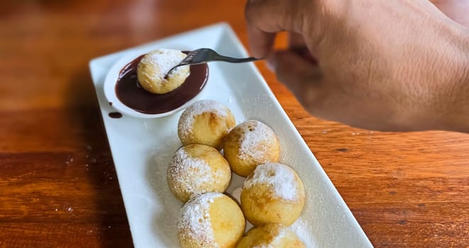 Homemade delicious sweet Dutch poffertjes mini pancakes with icing powdered sugar and chocolate fillings with additional chocolate sauce for cooking multimedia content creation