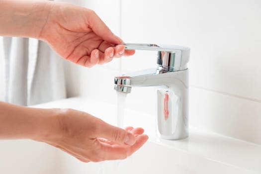 Sustainable use of natural resources. Woman is opening and closing water flow tap. Water running from chrome faucet. Using water resources concept, environmental protection concept