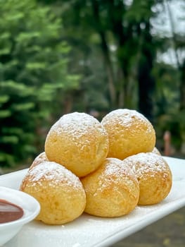 Homemade delicious sweet Dutch poffertjes mini pancakes with icing powdered sugar and chocolate fillings with additional chocolate sauce for cooking multimedia content creation