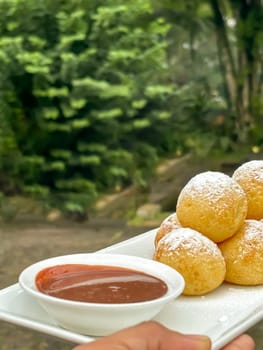 Homemade delicious sweet Dutch poffertjes mini pancakes with icing powdered sugar and chocolate fillings with additional chocolate sauce for cooking multimedia content creation