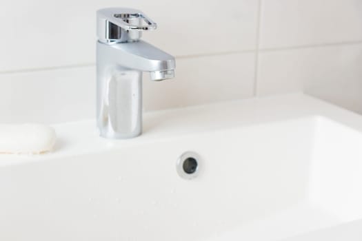 Modern bathroom chrome faucet, white tiles wall, water tap and sink with soap, cleanness concept, close water, saving natural recourses concept banner with copy space