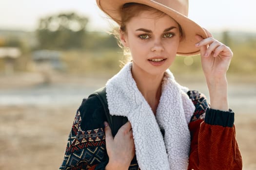 Desert wanderlust woman in hat and scarf standing in sundrenched desert landscape