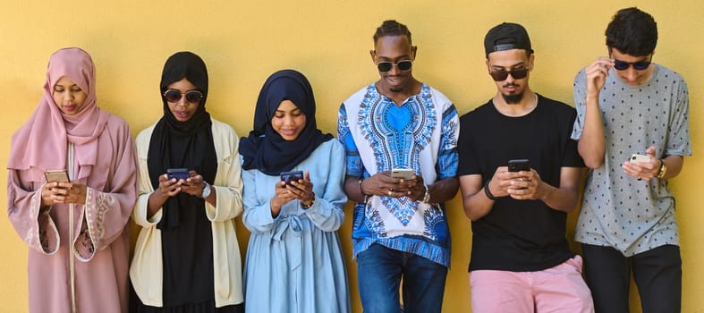 A diverse group of teenagers standing together against a wall, engrossed in their smartphones, showcasing modern connectivity and social interaction.