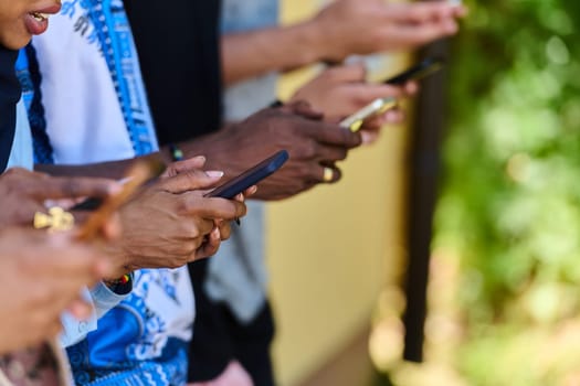 A diverse group of teenagers standing together against a wall, engrossed in their smartphones, showcasing modern connectivity and social interaction.