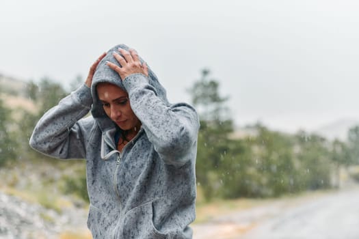 A determined woman finds solace in the rain as she rests after an intense run, embracing the rejuvenating rhythm of the falling raindrops