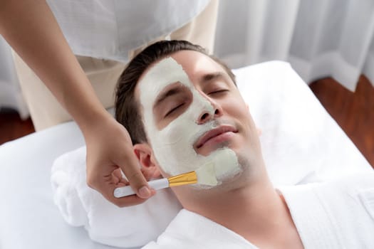 Serene ambiance of spa salon, man customer indulges in rejuvenating with luxurious face cream massage with modern daylight. Facial skin treatment and beauty care concept. Quiescent