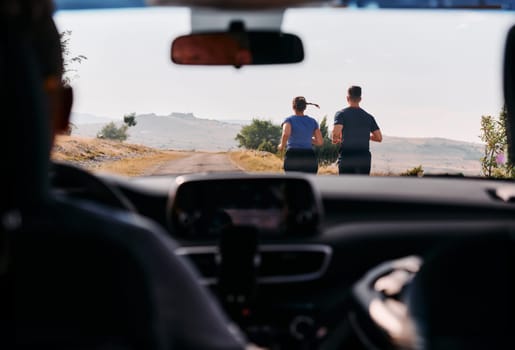 A romantic couple is captured running outdoors from the perspective of a car, embodying adventure and togetherness in their journey