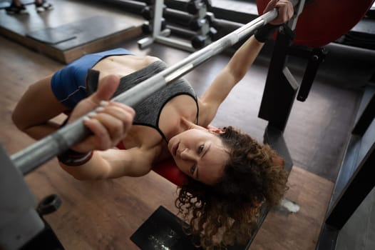 Middle aged woman doing bench press at the gym