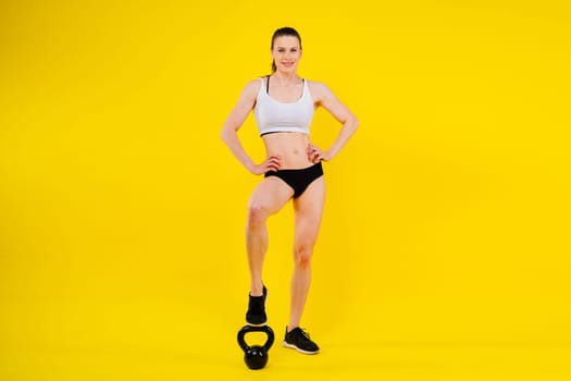 Attractive young athlete with a muscular body exercising crossfit workout with kettlebell.