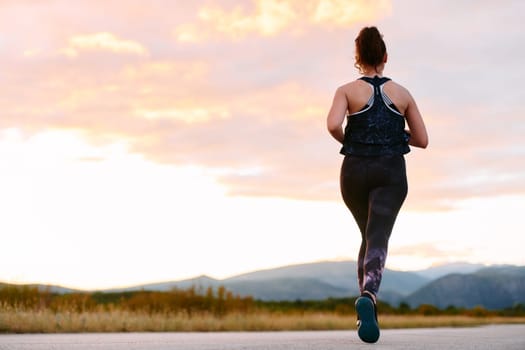 A determined athlete runs confidently under the sun, surrounded by stunning natural scenery, showcasing strength and resilience in her pursuit of fitness