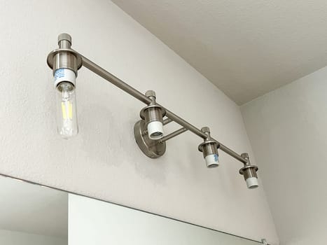 Denver, Colorado, USA-November 23, 2023-A modern bathroom light fixture mounted above a mirror, featuring a sleek metal design and LED bulbs. The fixture, with its minimalistic and contemporary look, enhances the bathroom ambiance and provides efficient lighting.